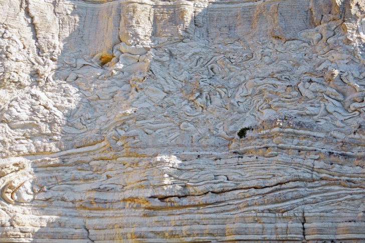 An approximately 40 m high cliff face showing a thick slump bed composed of interbedded carbonates and calcarenites, with coherent folding in its lower part and more chaotic deformation above (Antipaxos island, NW Greece, Pre-Apulian unit).